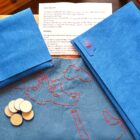 Full layout of the game including a hand-stitched leather map board, wooden tokens, and vibrant suede blue pouchs